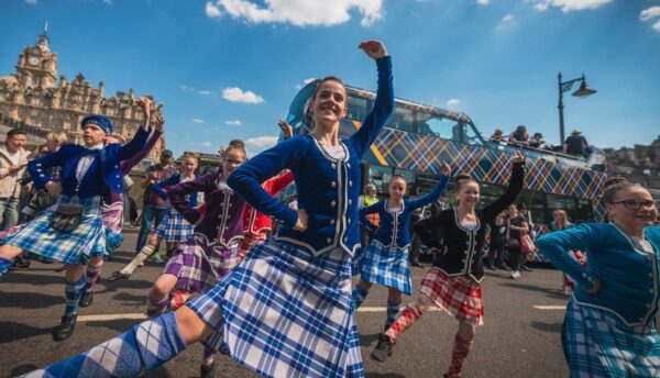 Edinburgh Tartan Parade dancers performing on the Royal Mile with Edinburgh Castle in the background