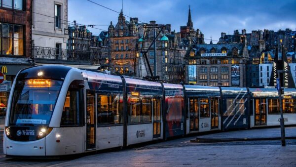 Edinburgh tram in the city centre at dusk with the Edinburgh skyline in the background