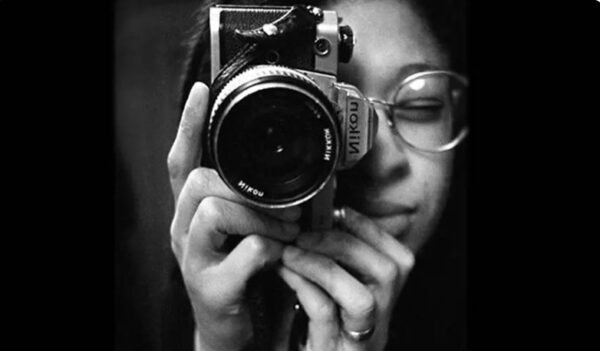 Sandra George holding a Nikon camera in a black and white photograph