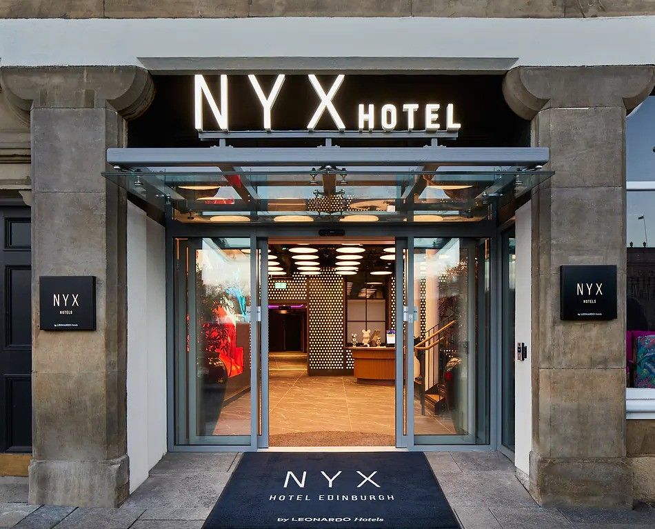 Entrance to NYX Hotel Edinburgh on Jeffrey Street showing the illuminated sign, glass canopy and stone facade
