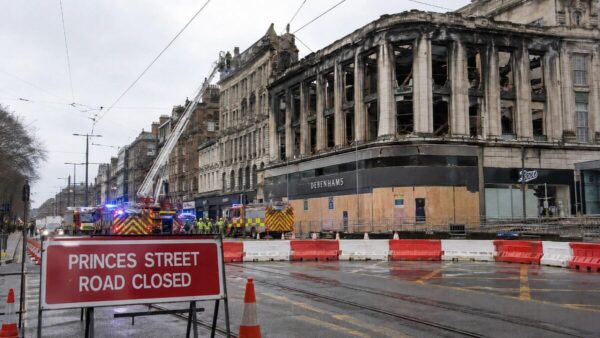 Fire-damaged former Debenhams building behind road barriers on Princes Street in Edinburgh