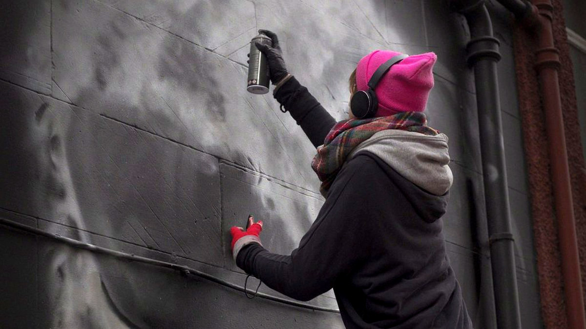 Leith artist Shona Hardie spray-painting a portrait of Arthur Williams on Arthur Street